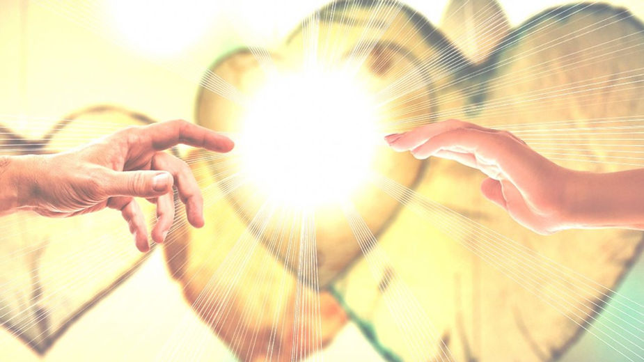 Imagen simbólica para afrontar el duelo: dos manos tocan un corazón brillante y flotante